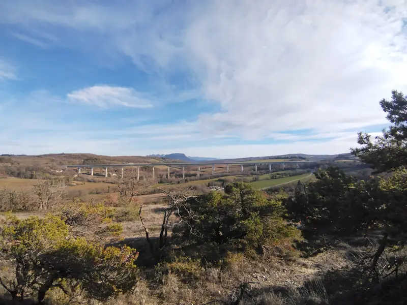 Vue depuis le parcours sur la campagne drômoise et un long viaduc, sous un grand ciel bleu
